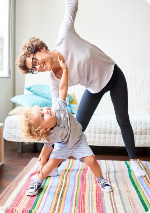 mom with daughter doing side leg stretch standing in the living room