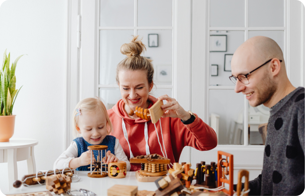 family playing with kid with wooden toys at the table